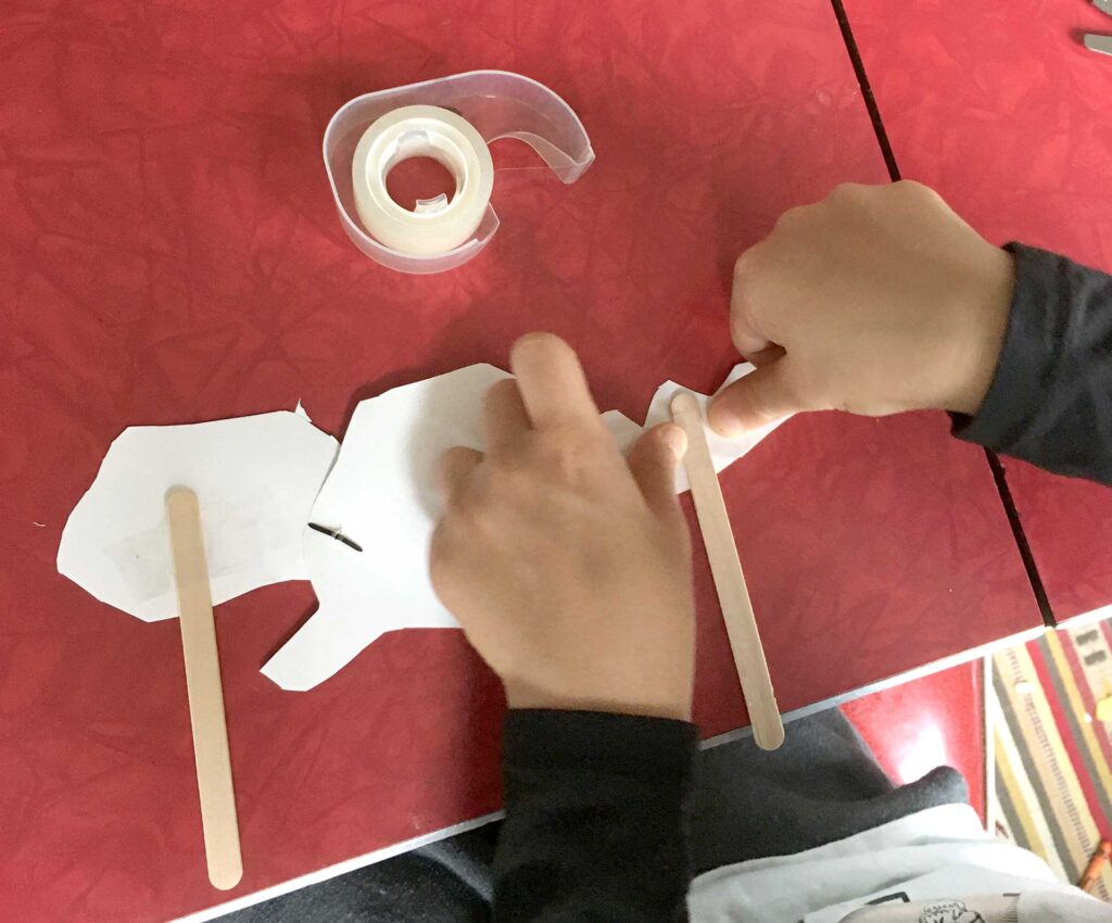 taping sticks on back of paper baby dragon puppet